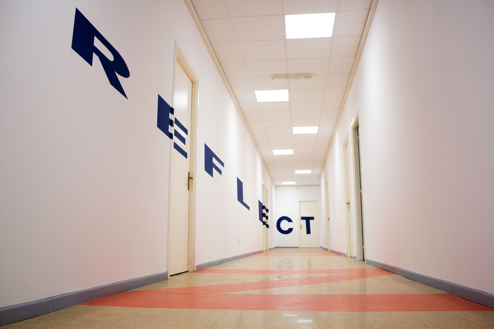 Corridor of the Unicollege Turin City College, lettered "Reflect"