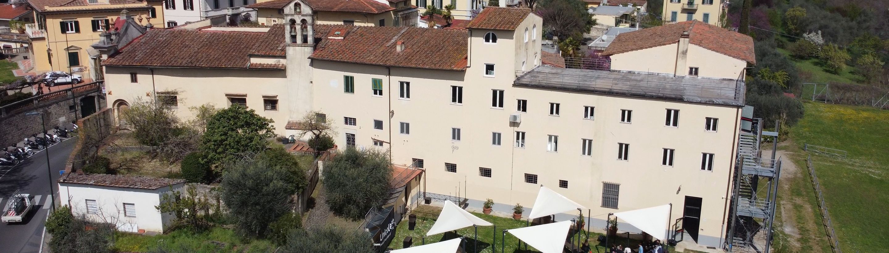 The villa of the Florence campus seen from the lawn, with the garden tents and the hills