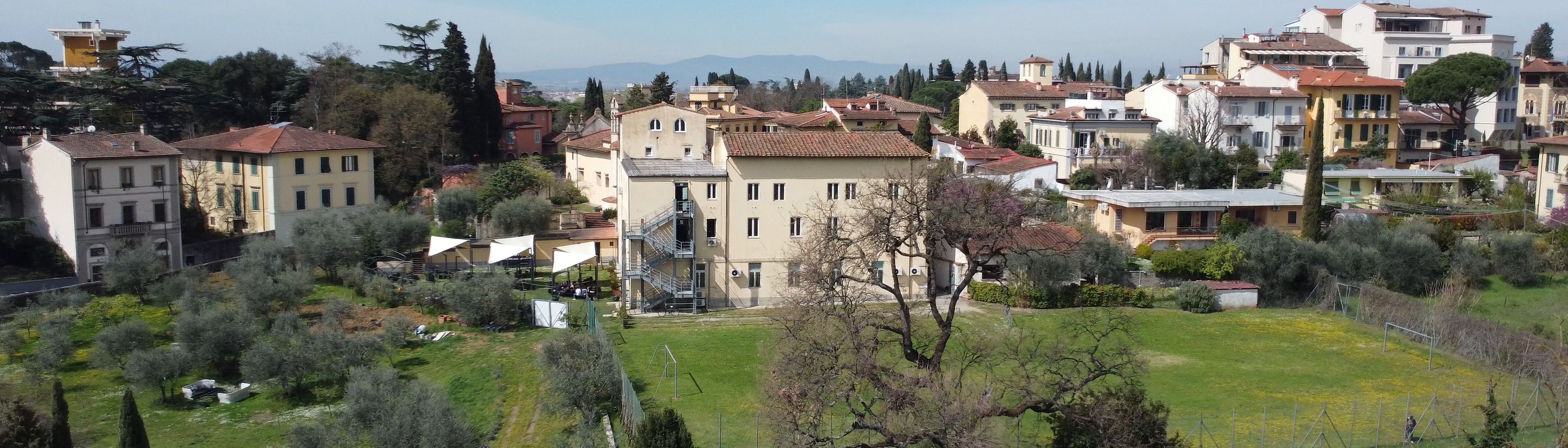 The villa and the lawn of the Florence campus with the hills and an open sky