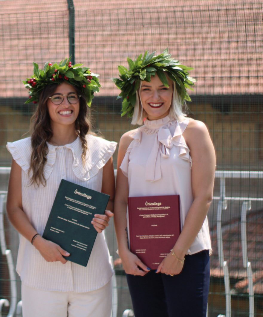 Two Unicollege graduates with laurel wreaths and diplomas
