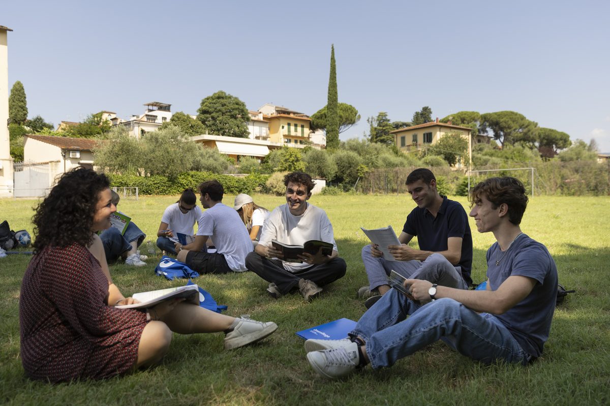 Unicollege students studying on the lawn with the hills of Florence behind